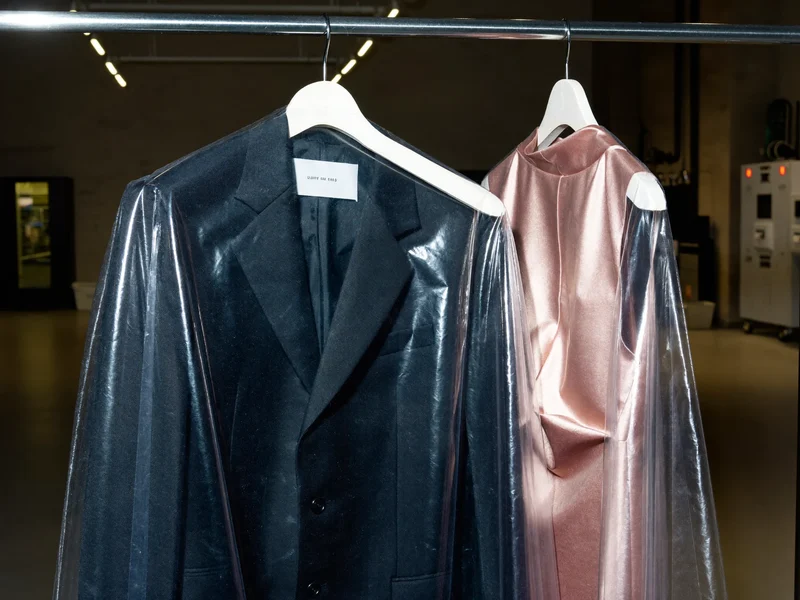 Costume sombre et robe en soie suspendus sous housses transparentes sur un rail en acier