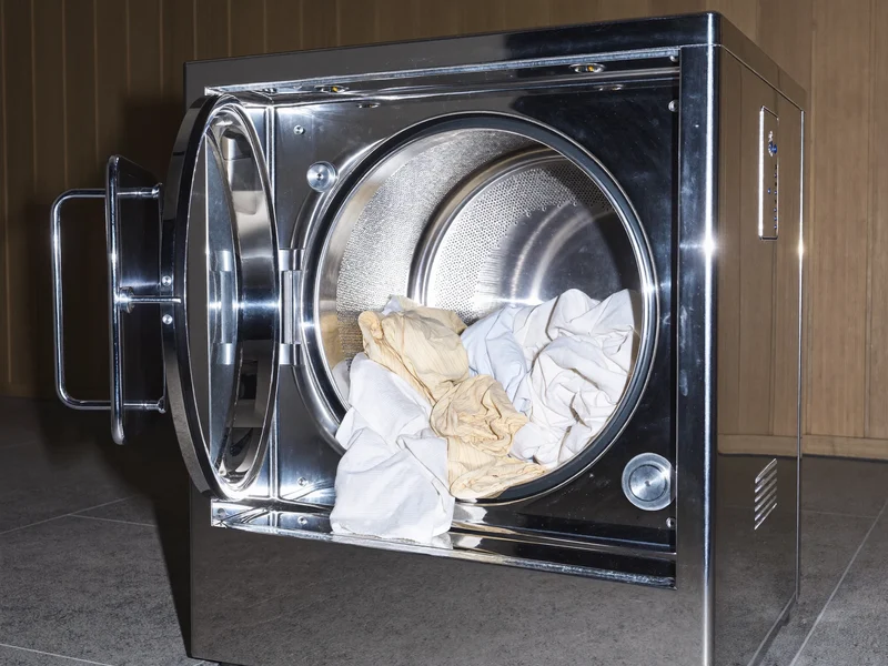 Intérieur d'une machine de nettoyage à sec ouverte avec un chargement de vêtements